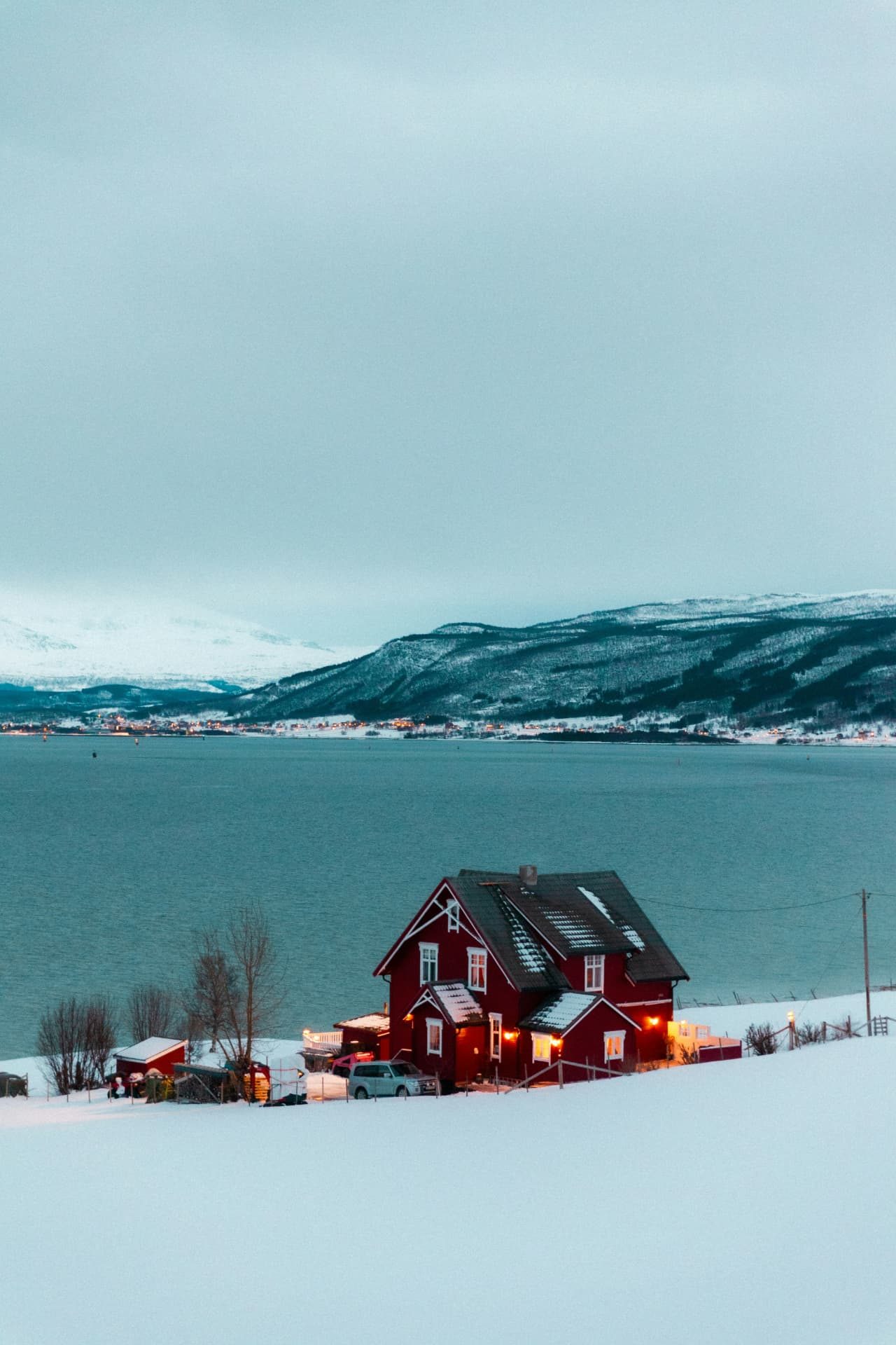 Rött bostadshus med upplysta fönster i ett snötäckt vinterlandskap